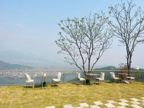 un grupo de sillas sentadas alrededor de una mesa junto a un lago en Pumdi Ghar Retreat en Pokhara