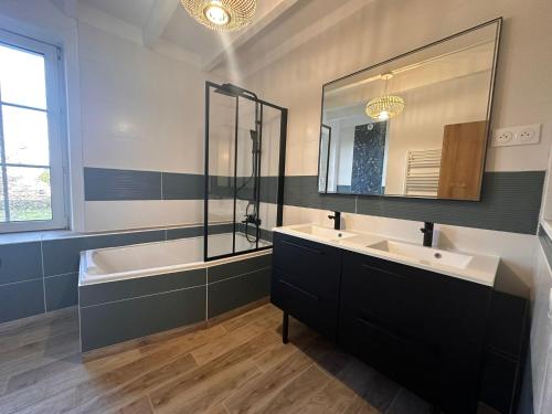 a bathroom with two sinks and a tub and a mirror at Les Jardins des 3 sœurs in Quettehou