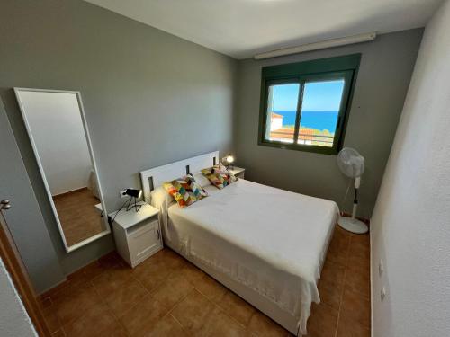 a bedroom with a white bed and a window at Apartamentos Mirador al Mar Altamar in Alcossebre