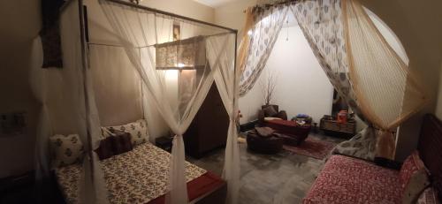 - une chambre avec un lit à baldaquin et une chaise dans l'établissement Home Away From Home, à Prayagraj