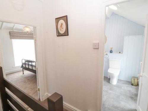 a bathroom with a toilet and a hallway with a staircase at Foxy Lady Cottage in Workington