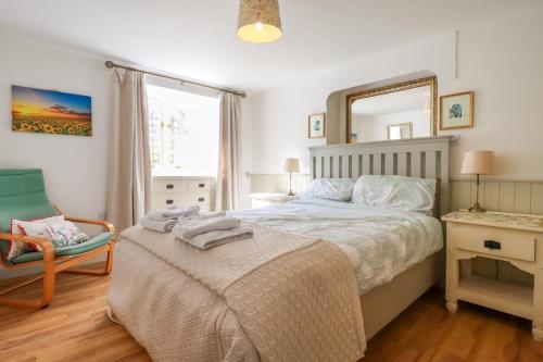 sypialnia z łóżkiem z lustrem i krzesłem w obiekcie Sunlight Cottage w mieście Truro