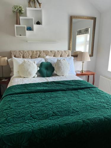 a bed with a green comforter and two pillows at Old Mill House in Larne