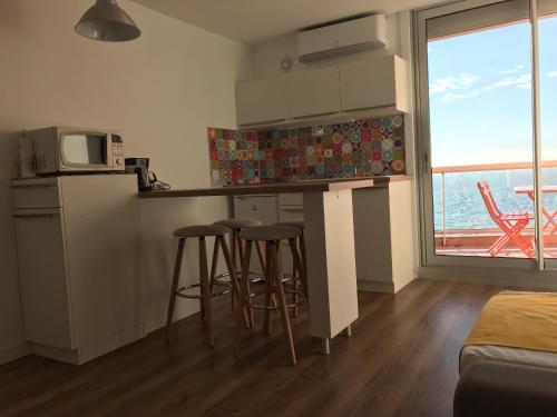 une cuisine avec tabourets et comptoir avec four micro-ondes dans l'établissement Studio vue mer, à Sète