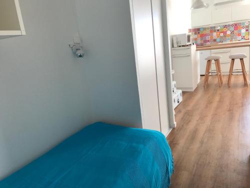 une chambre avec un lit bleu et une cuisine dans l'établissement Studio vue mer, à Sète