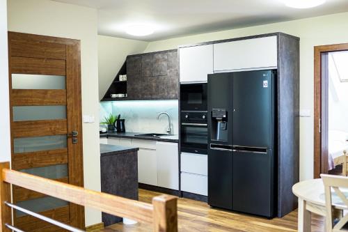 a kitchen with a black refrigerator and white cabinets at Spokojny Apartament u Słodyczki w Kluszkowcach in Kluszkowce