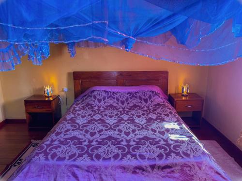 1 dormitorio con 1 cama de color púrpura y 2 mesitas de noche en Le Famanta - Hotel & Restaurant, en Fort Dauphin