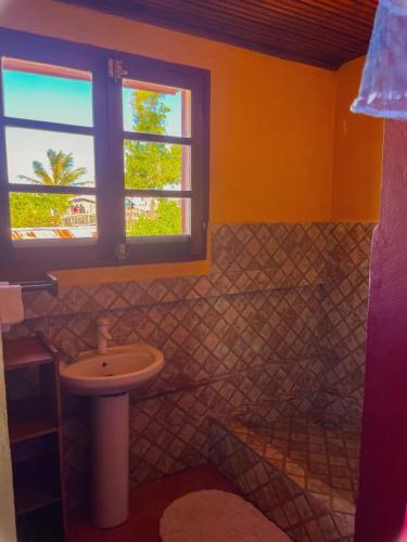 a bathroom with a sink and a toilet and a window at Le Famanta - Hotel & Restaurant in Fort Dauphin