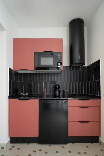 a kitchen with red and black cabinets and a microwave at La PINTORESCA ''TIERRA'' - TEATRO ROMANO MERIDA in Merida