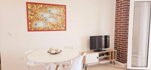 Apartments Luma في هفار: غرفة طعام مع طاولة بيضاء وتلفزيون