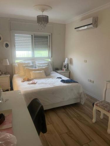 sypialnia z dużym białym łóżkiem i drewnianą podłogą w obiekcie בית כפרי בנורדיה w mieście Gannot Hadar