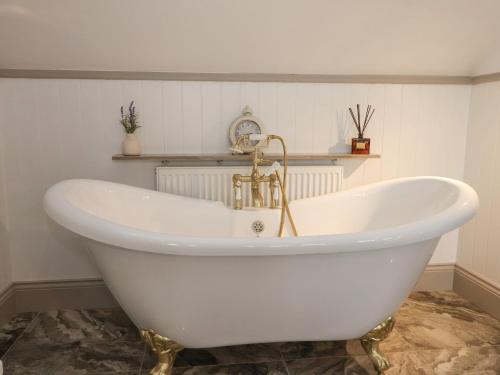 a white bath tub with a gold faucet in a bathroom at 4 Lock View in Skipton