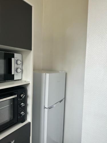einen weißen Kühlschrank in einer Küche neben einer Mikrowelle in der Unterkunft Appartement confort in Vanves
