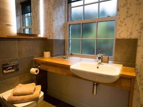 uma casa de banho com um lavatório, uma janela e um WC. em 4 Fir Garth em Ambleside