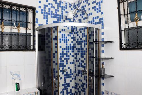 a shower in a bathroom with blue and white tiles at TANISHIA APARTMENTS in Mombasa