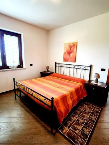 a bedroom with a bed with an orange bedspread at la casa di simone in Torre Tre Ponti