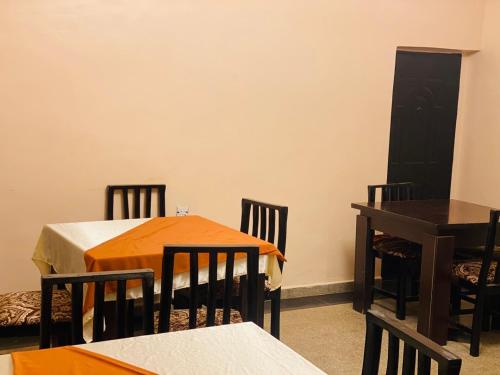 a dining room with two tables and chairs and a black door at Havilah Suites Ltd, Nnewi in Nnewi