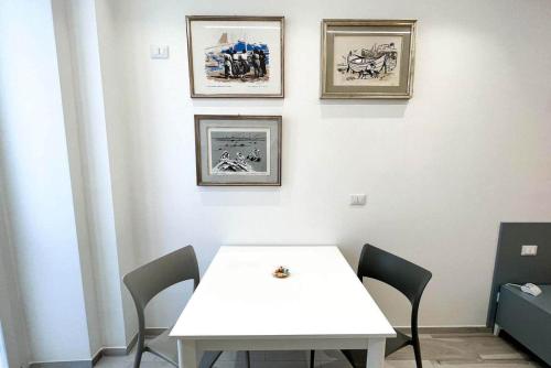 a white table with chairs and pictures on a wall at La Retara Affittacamere in San Benedetto del Tronto