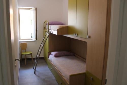 a room with two bunk beds and a ladder at Appartamento smart con splendido mare sotto casa in Capo Rizzuto