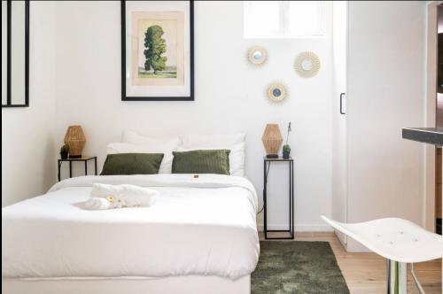 - une chambre blanche avec 2 lits et une table dans l'établissement Studio 2 Joli studio neuf veranda d ete bords de Marne 5 km paris, à Champigny-sur-Marne