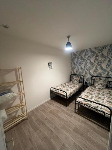 a room with two beds and a shelf in it at Logement Bonheur 
