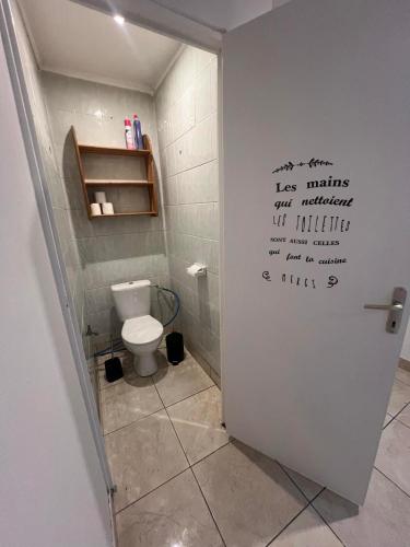 a bathroom with a toilet and a sign on the door at Logement Bonheur 