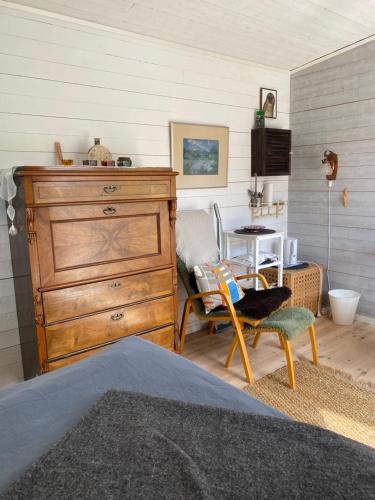 ein Schlafzimmer mit einer Kommode, einem Stuhl und einem Tisch in der Unterkunft Sigridsro in Alingsås