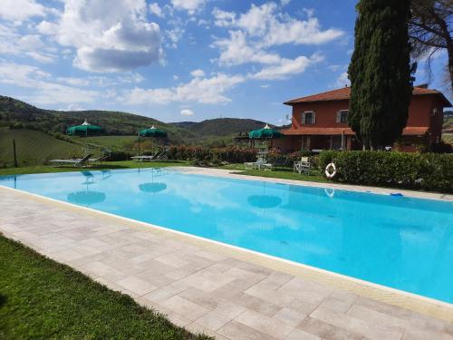 a large blue swimming pool in front of a house at Villa Del Sole in San Gimignano