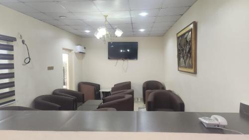 una sala de espera con sillas y TV en la pared en Ceetran Hotels, en Port Harcourt