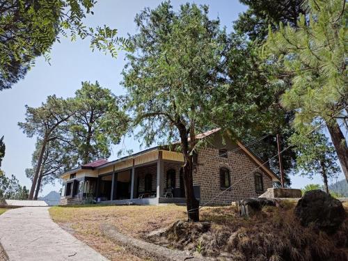 a house with a tree in front of it at Batrasi Dak Bungalow in Uttar Shisha