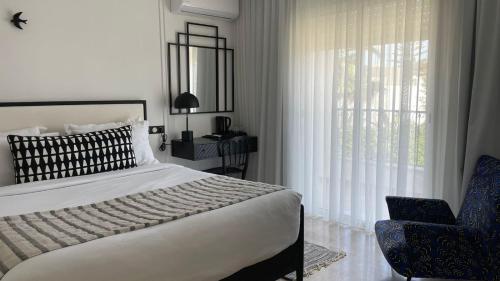 Misk Villa - Boutique Hotel & Spa في سيدي بو سعيد: غرفة نوم بسرير وكرسي ونافذة