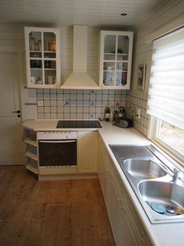 a kitchen with white cabinets and a sink at Gilou in Koekelare