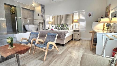 a bedroom with a bed and two chairs and a table at Fleur du Soleil Luxury Guesthouse in Franschhoek
