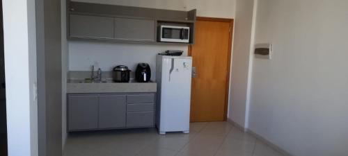 La cuisine est équipée d'un réfrigérateur blanc et d'un four micro-ondes. dans l'établissement Apartamento nas dependencias do Recinto de Rodeio em Barretos, à Barretos
