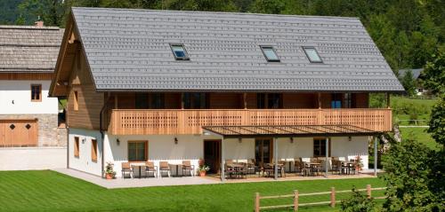 een groot huis met een houten dak met tafels en stoelen bij PRIVILLAGE Stare - B&B in Bohinj