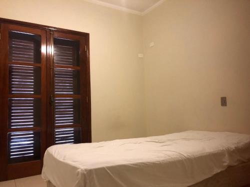 a bedroom with a bed and a wooden door at Quarto com varanda tipo Airbn b Vista Panorâmica Livre da Cidade in Americana