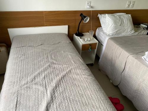 a bedroom with two beds and a lamp on a night stand at Apart Hotel Marinas Tamandaré in Recife