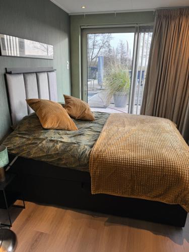 Un dormitorio con una cama con almohadas y una ventana. en De Gouwe Stek, en Landsmeer