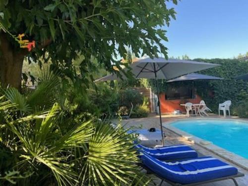a pool with blue lounge chairs and an umbrella at Chambre FLORENCE - MAS SAINT LOUIS in Aigues-Mortes