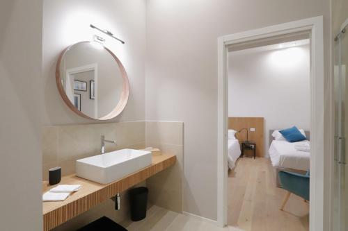 een badkamer met een wastafel, een spiegel en een bed bij [Soggiorno di Lusso] nel Centro Storico di Modena in Modena