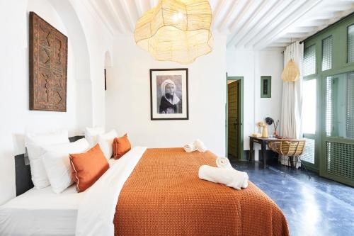 a bedroom with a large bed with an orange blanket at Riad Dar Nakous in Marrakesh
