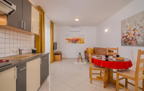 a kitchen and living room with a red table and chairs at Apartments Kvarner in Malinska