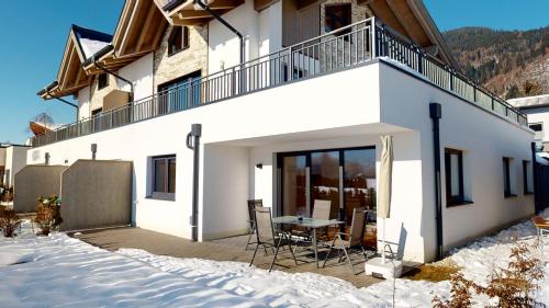 a white house with a table and chairs in the snow at Kitzview Idyll in Zell am See