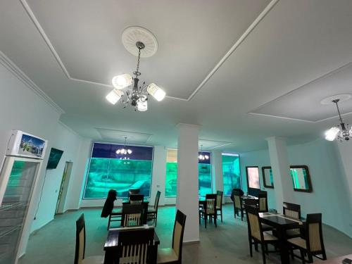 una sala da pranzo con tavoli, sedie e ventilatore di Hotel Adriatik Shengjin a Shëngjin