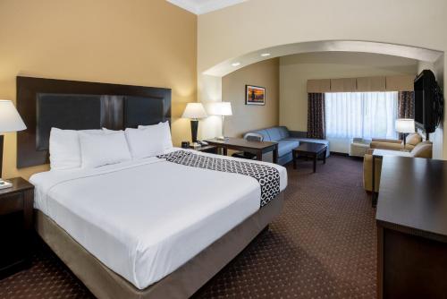 a hotel room with a large bed and a living room at La Quinta by Wyndham Houston New Caney in New Caney
