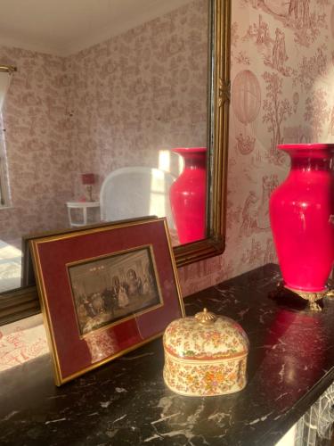 two red vases on a table with a picture and a frame at Château de Roberville in Machemont