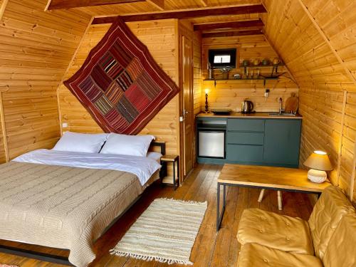 a bedroom with a bed and a kitchen in a cabin at Kazbegi Kuro Cottages in Stepantsminda