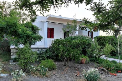 a white house with a red door and trees at Sea Breeze Beach House in Skiros