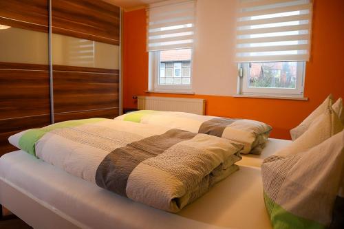 Bett in einem Zimmer mit orangefarbenen Wänden und Fenstern in der Unterkunft Ferienwohnung Andres in Drübeck