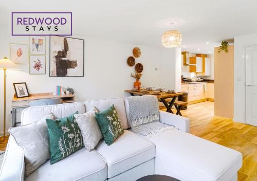 a living room with a white couch and a kitchen at BRAND NEW! 3 Bed 2 Bath House, NEAR HOSPITAL, With FREE x2 Parking & Wi-Fi By REDWOOD STAYS in Basingstoke